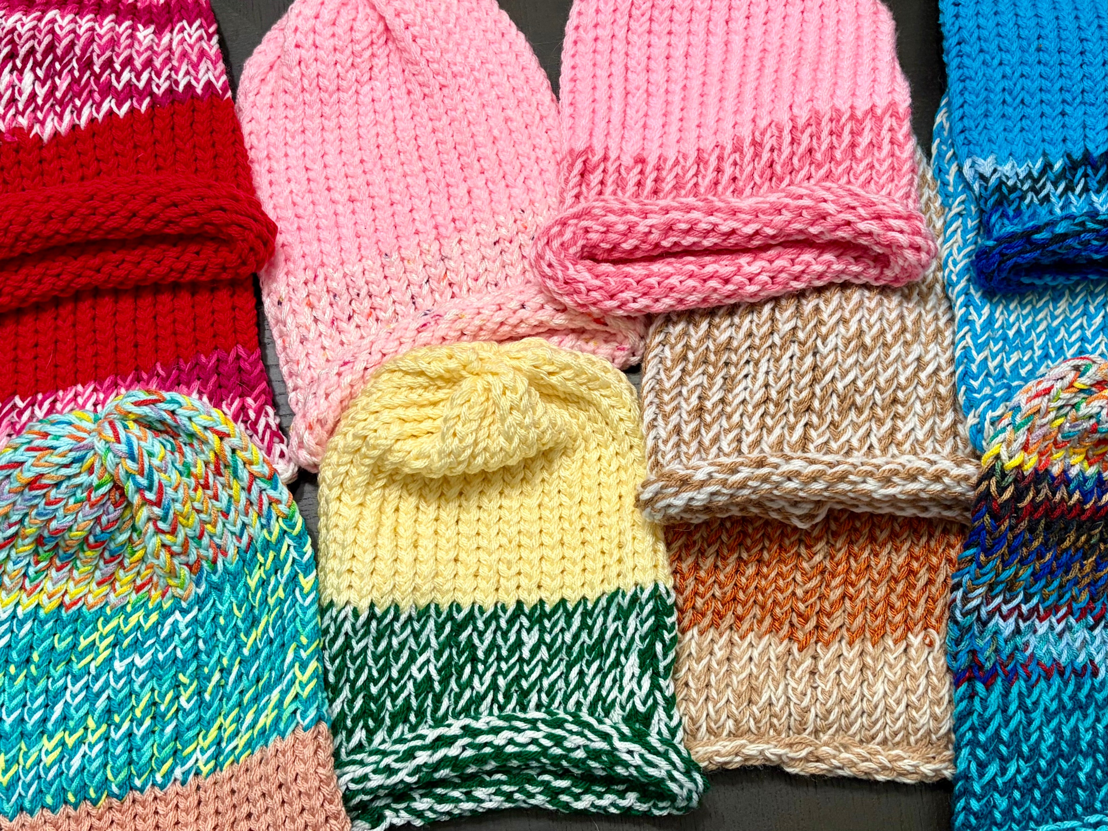 Hand-knitted beanie hats in various colors laid flat