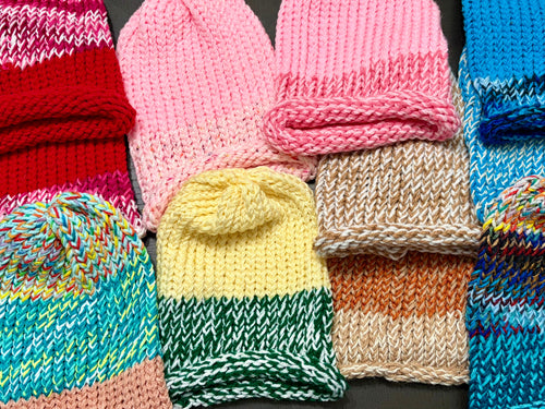 Hand-knitted beanie hats in various colors laid flat